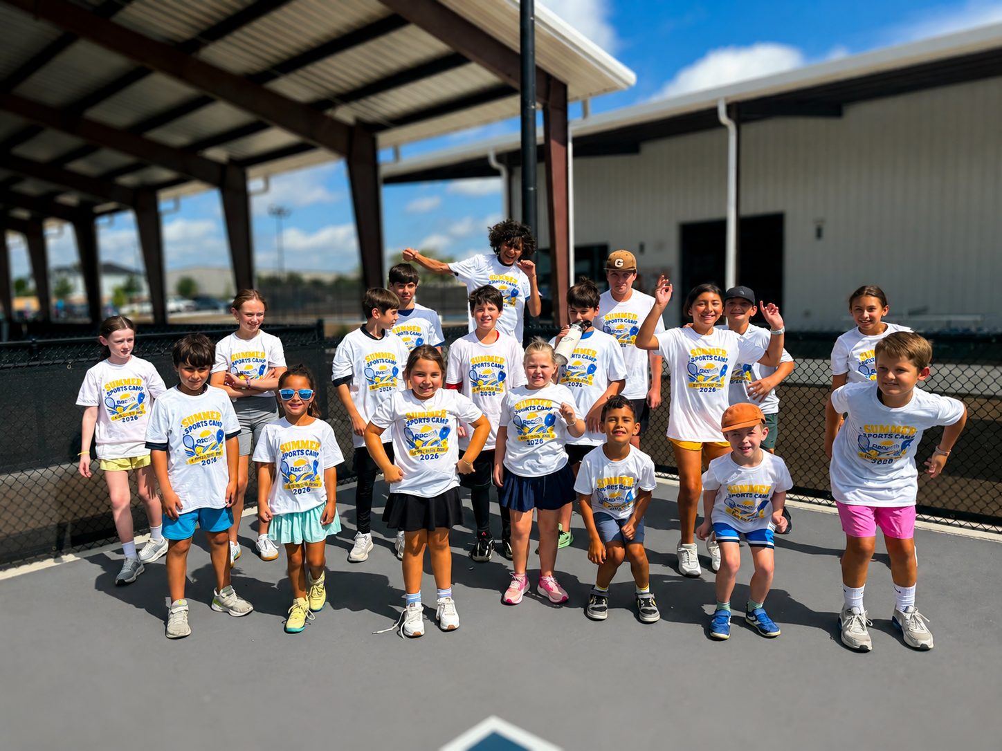 Campers in RacFit camp shirts on the covered courts at RacFit in Buda, Texas